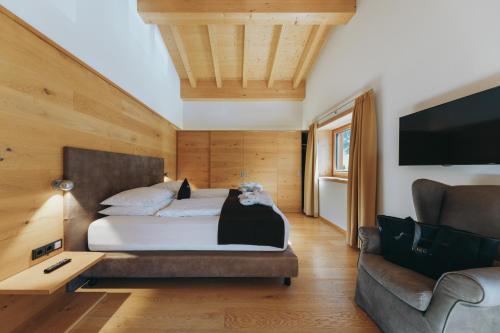 a bedroom with a bed and a couch and a tv at Apart-Hotel Laurus Lech in Lech am Arlberg