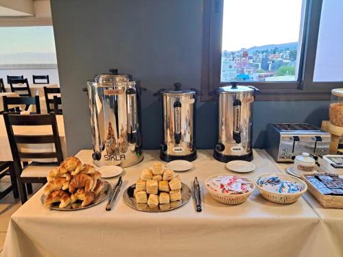 a table topped with plates of pastries and silver appliances at Central Suites Hotel in Villa Carlos Paz