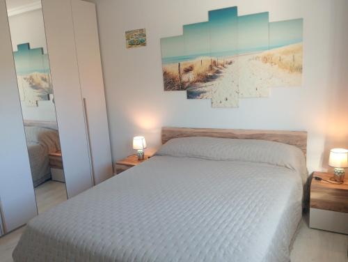 a bedroom with a white bed and two lamps on tables at La casa de la avioneta in Argoños