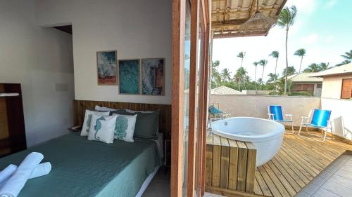 a bedroom with a tub and a bed and a balcony at Pousada Oceano Atlântico in Barra Grande