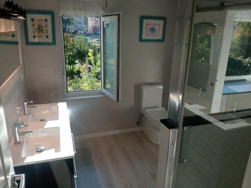 a bathroom with two sinks and a toilet and two windows at La casa de la avioneta in Argoños