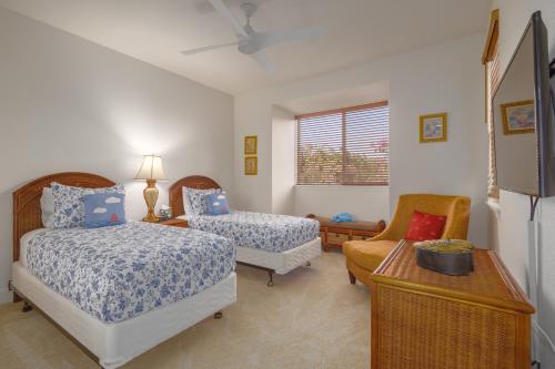 Un dormitorio con dos camas y una silla. en Relax Unwind in Paradise Kulalani 203, en Waikoloa