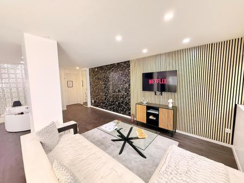 a living room with a white couch and a tv at Les Suites Bisous Metz - Jacuzzi & Private Sauna in Metz