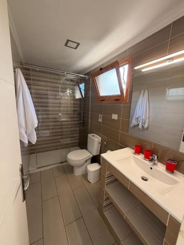 a bathroom with a toilet and a sink and a mirror at Secret Bungalow, Los Arcos in San Bartolomé