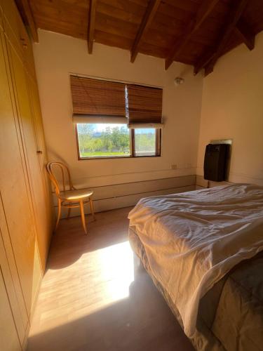 a bedroom with a bed and a chair and a window at Cabaña Cordón Situación in Trevelín