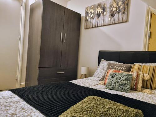 a bedroom with a bed with a brown cabinet at Beautiful Rooms near Hampton Court in Molesey