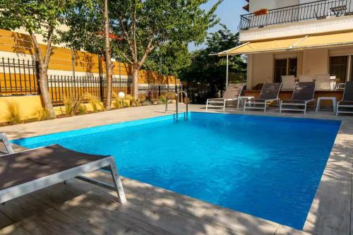 a large blue swimming pool with chairs around it at Heated Pool Villa in Thessaloniki - Urban Oasis in Thessaloniki