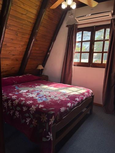 a bedroom with a bed in a attic with windows at Cabañas Pindahue - Alojamineto Epehuen in Villa Carlos Paz