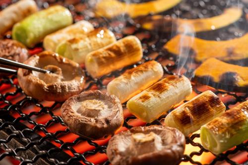 a bunch of food cooking on a grill at KAMENOI HOTEL Kusatsu Resort in Kusatsu