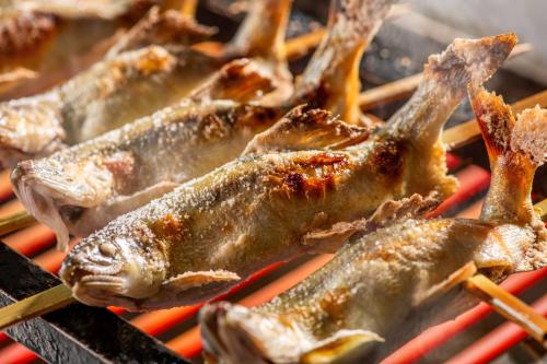 a bunch of fish cooking on a grill at KAMENOI HOTEL Kusatsu Resort in Kusatsu