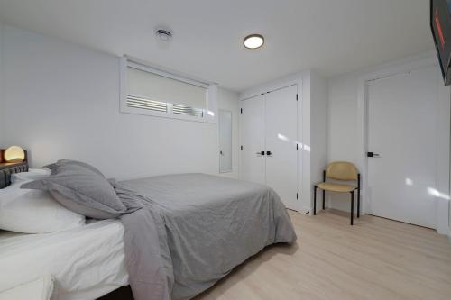 a white bedroom with a bed and a chair at Modern Suite by Hospital 2 Near Transit, Wi-Fi, Netflix in Edmonton