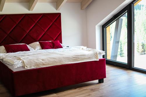 a red bed in a room with a large window at Chata Andromeda in Oravská Lesná