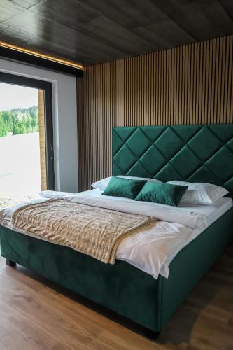a bedroom with a large bed with a green headboard at Chata Andromeda in Oravská Lesná