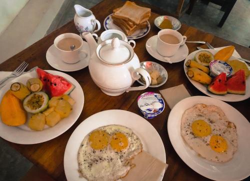 une table en bois avec des assiettes d'œufs et de fruits dans l'établissement Little jay"s villa, à Batigama