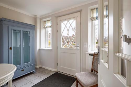 a hallway with a blue door and windows at Haus Sofie in Utersum