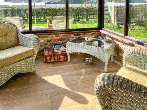 Una sala de estar con sillas y una mesa y ventanas. en The Old Chapel, en Burshill