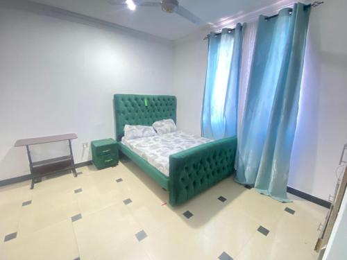 1 dormitorio con cama verde y cortinas azules en Pumzika Hostings, en Mombasa