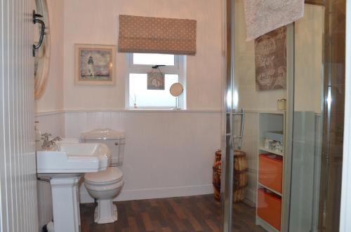 ein Badezimmer mit Toilette und Waschbecken und einem Fenster in der Unterkunft 32 Benbane Park in Portballintrae
