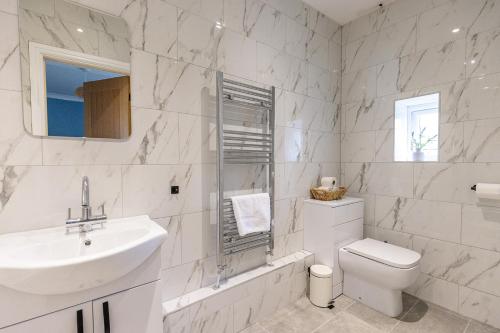 a white bathroom with a sink and a toilet at EASTCOTE FARM - Spacious 5-Bed Home with Views, Garden & Playroom in Silloth