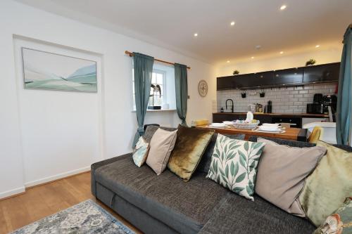 a living room with a couch and a kitchen at Little Gem in the Forest of Dean! Hot tub, Private garden, Dog Friendly, Smart TVs and Beautiful Historic Village Location! in Saint Briavels