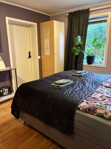 a bedroom with a bed with a black comforter and a window at Comfortable stay near Gothenburg with private sauna and coast nearby in Billdal