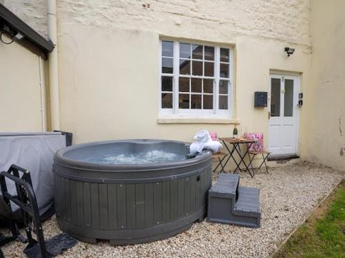 a large hot tub sitting outside of a house at Little Gem in the Forest of Dean! Hot tub, Private garden, Dog Friendly, Smart TVs and Beautiful Historic Village Location! in Saint Briavels