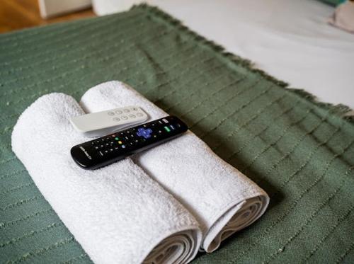 a remote control sitting on top of towels on a bed at Little Gem in the Forest of Dean! Hot tub, Private garden, Dog Friendly, Smart TVs and Beautiful Historic Village Location! in Saint Briavels