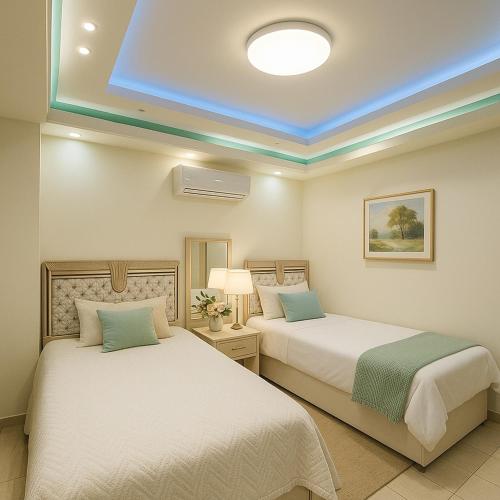 two beds in a bedroom with a blue ceiling at Madinty Stylish Stay in B6 in Madinaty
