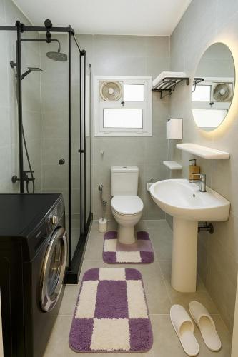 a bathroom with a toilet and a sink and a washing machine at Madinty Stylish Stay in B6 in Madinaty