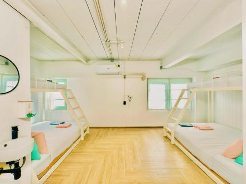 two bunk beds in a room with a wooden floor at Green Group Stay Bangkok - Near Khaosan Road in Bangkok