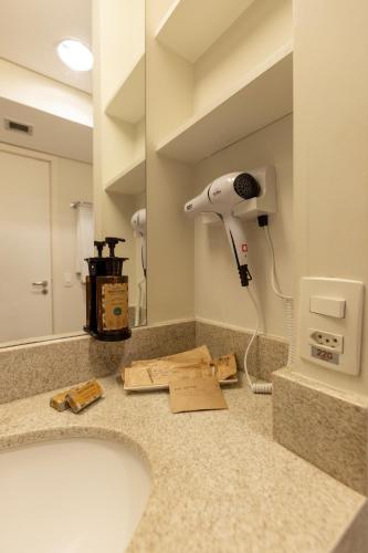 a bathroom counter with a hair dryer and a mirror at Mercure Jundiai Shopping in Jundiaí