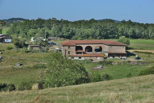 a large brick building in a field with trees at Gîte de la Ferme des Bourettes in Haute-Rivoire