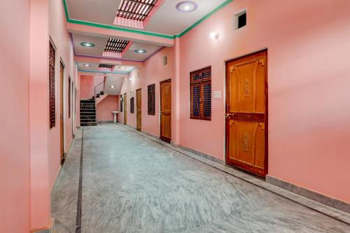 an empty corridor with pink walls and wooden doors at Hotel O Blue Moon in Prayagraj