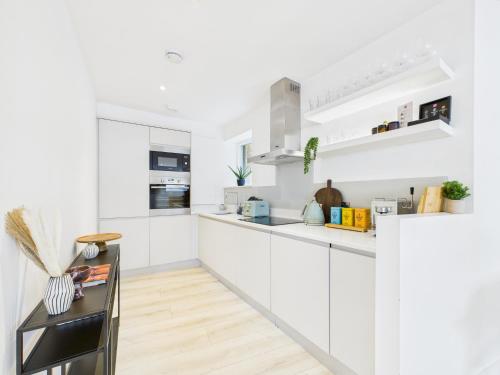 a white kitchen with white cabinets and a wooden floor at Be London - Borough Market Residences in London