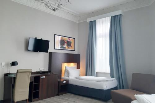 a hotel room with a bed and a desk at Garner Hotel Hamburg - Graf Moltke by IHG in Hamburg