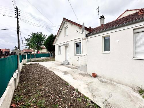 a white house with a fence next to a yard at Cocon tout confort à 25 min de Paris in Sevran