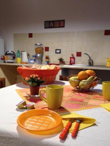 a table with plates and cups and a bowl of fruit at Domoruja B&B in Sassari