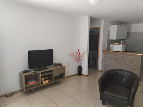 a living room with a television and a chair at Verde in Cuchilla Alta