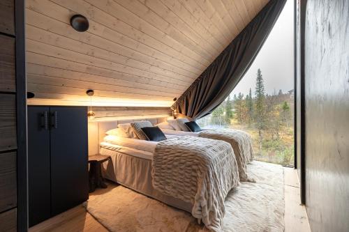 two beds in a room with a window at Aura Arctic Chalets - Grand Panoramic & Grand Hideaway in Saariselka