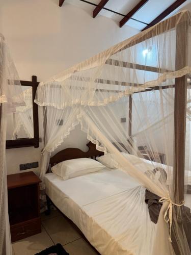 a bedroom with a canopy bed with white mosquito nets at Taco Super Place in Unawatuna