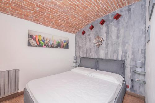 a white bed in a room with a brick wall at Ladyemma in Turin