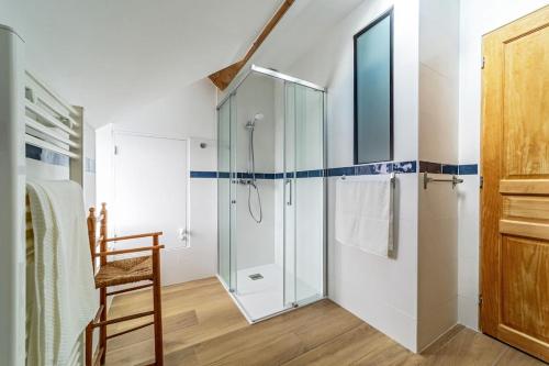 a bathroom with a shower and a wooden chair at La Girouette in Bazainville