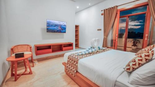 a bedroom with a bed and a desk and a tv at Villa Griya Anyar Ubud in Ubud