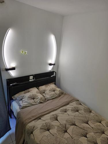 a bed in a room with a white wall at Studio Antigone centre ville in Montpellier