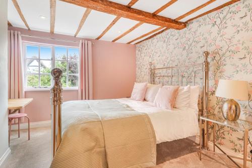 a bedroom with a bed and a desk and a window at Quaint Cottage by the Castle in Kenilworth