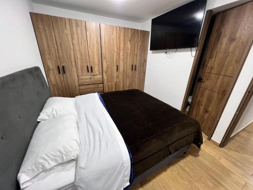 Un dormitorio con una cama y un armario de madera. en Moderno apartamento frente a viva mall, en Tunja