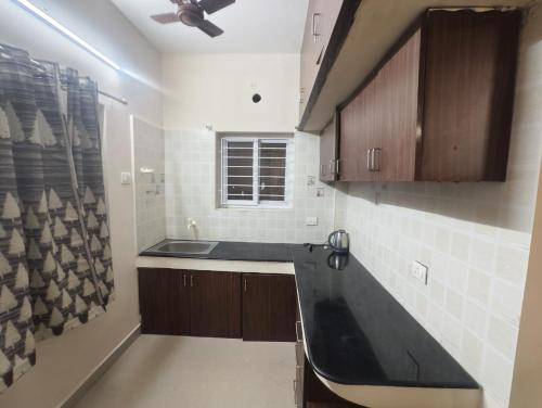 a kitchen with a sink and a black counter top at Kavin,s stays in Tirupporūr