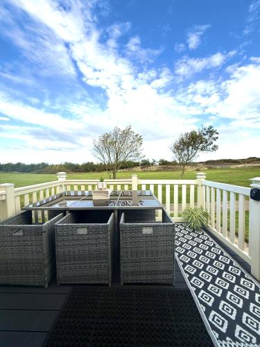 a patio with wicker chairs and a grill on a deck at Seashell Retreat in Scarborough