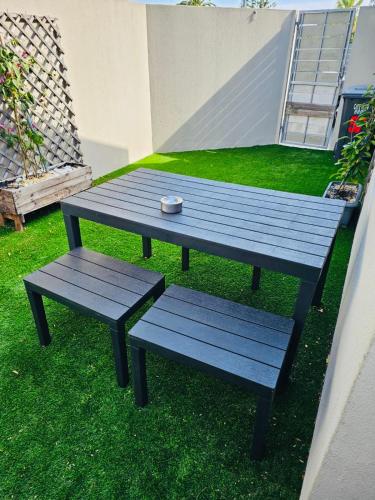 een picknicktafel en twee banken op het gras bij Blouberg Rise Cottage in Kaapstad
