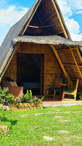 a house with a thatched roof with a table and a chair at Ten Foundations in Balayan